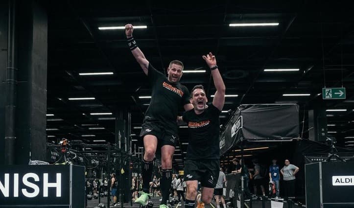 Zwei Athleten jubeln beim Zieleinlauf eines HYROX-Rennens